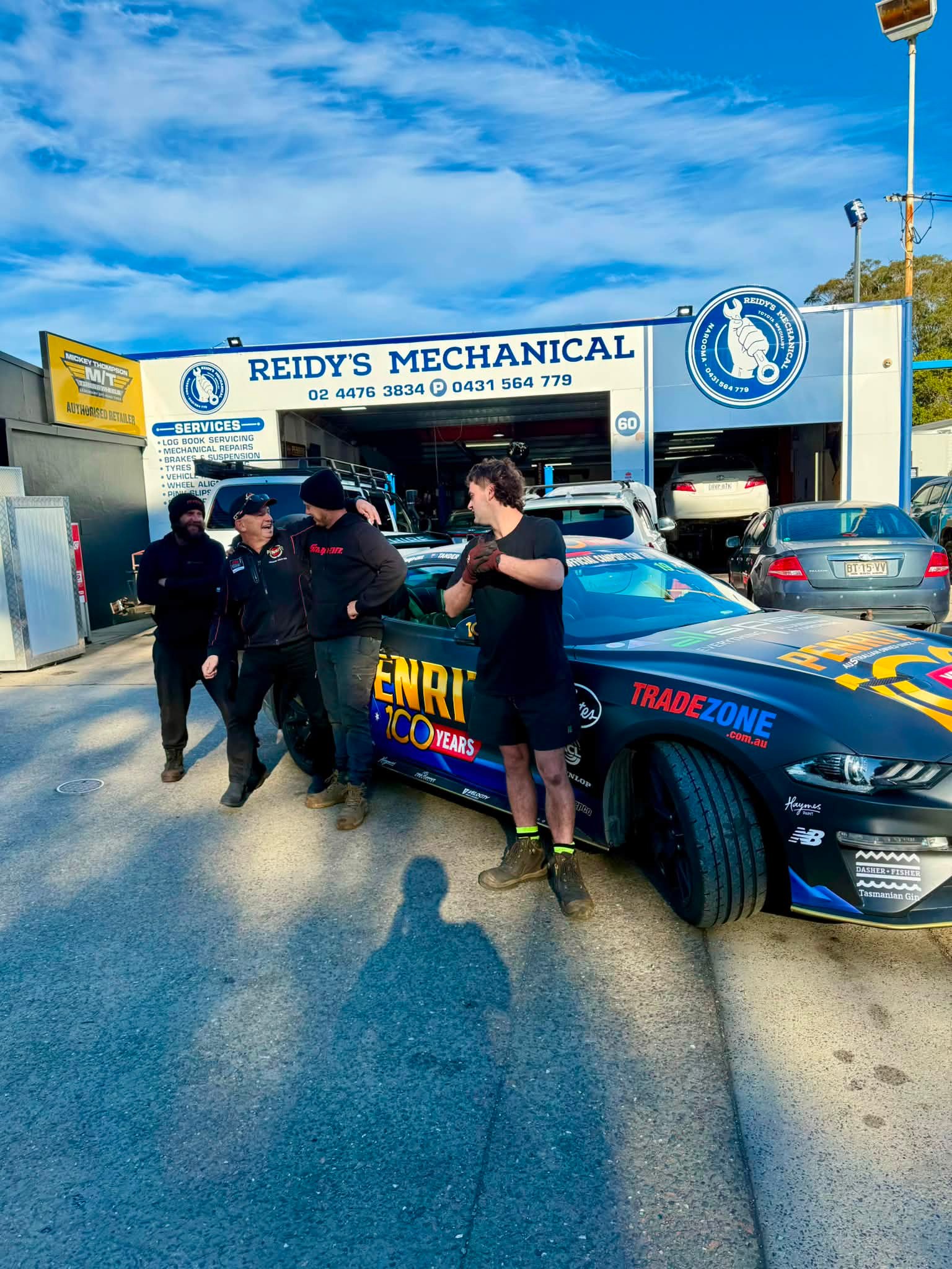 The crew outside the roller door with a Penrite liveried race car